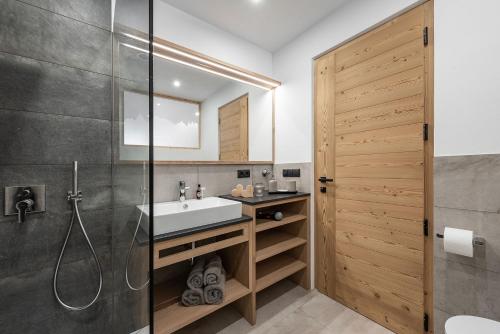 a bathroom with a sink and a glass shower door at Apartment Mittermanting in Villnoss