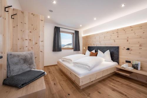 sypialnia z dużym białym łóżkiem i krzesłem w obiekcie Apartment Mittermanting w mieście Villnoss