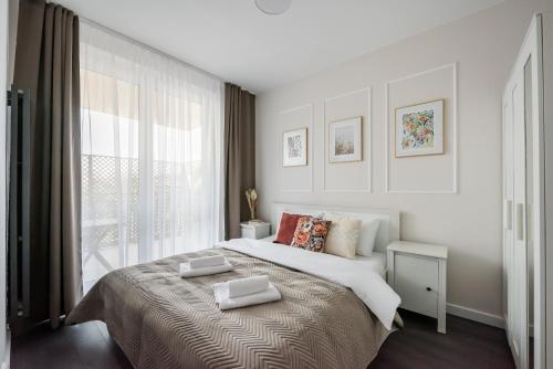 Wola Park Lovely Apartment - near Metro في وارسو: غرفة نوم بيضاء مع سرير كبير ونافذة