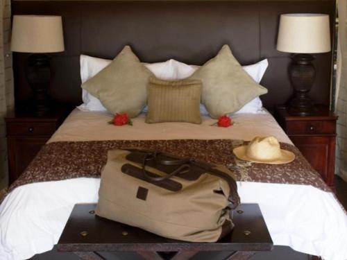 a bag on a bed with a hat on it at Mjejane River Lodge in Hectorspruit