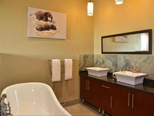 a bathroom with a bath tub and two sinks and a bath tub at Mjejane River Lodge in Hectorspruit