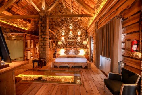 a bedroom with a bed in a log cabin at Hotel Xaluca Spa Aguelmame Sidi Ali in Aguelman