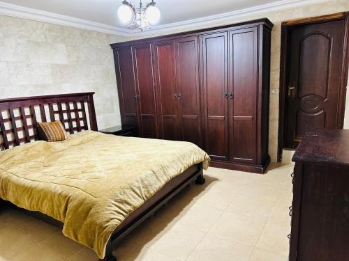 a bedroom with a bed and wooden cabinets at شقق الياسمين in Jerash