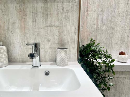 a white sink in a bathroom with a plant at Gorgeous Newly Renovated 2 Double Bed Flat in Swansea