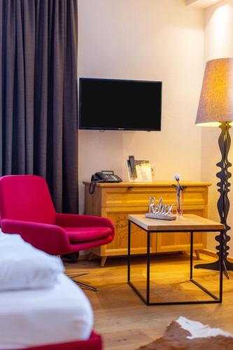 a hotel room with a red chair and a table at Hapimag Ferienwohnungen Zell am See in Zell am See