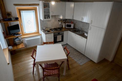 uma cozinha com uma mesa e uma mesa e cadeiras em Casa Claudia - Casa Vacanze em Domegge di Cadore