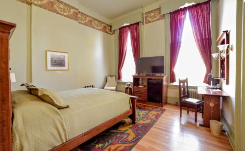a bedroom with a bed and a desk and a television at Oneida Community Mansion House in Oneida