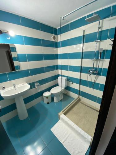 Pensiunea COCO في Năsăud: حمام من اللون الأزرق والأبيض مع دش ومغسلة