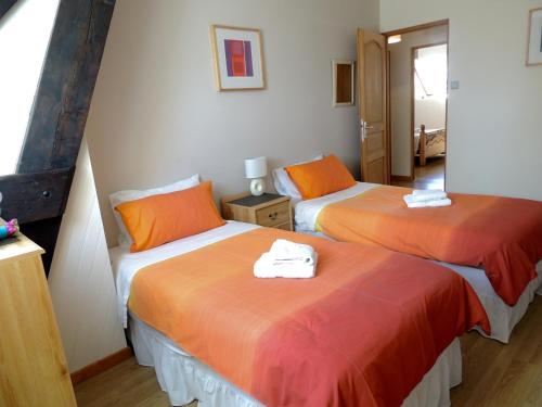 2 bedden met oranje en witte lakens in een kamer bij Chestnut cottage (Les Gîtes Champêtres) in Sainteny