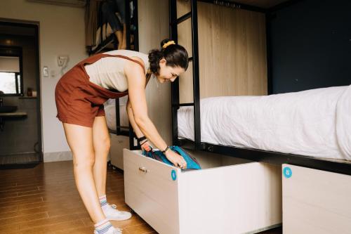 a woman opening a drawer in a room with two bunk beds at The Cuckoo's Nest Hostel and Bar managed by Hoianese in Hoi An