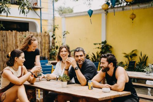 a group of people sitting at a table at The Cuckoo's Nest Hostel and Bar managed by Hoianese in Hoi An