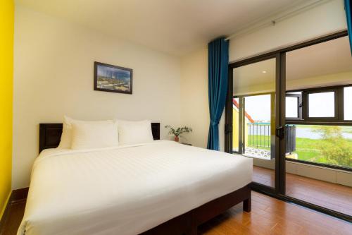 a bedroom with a large bed and a large window at The Cuckoo's Nest Hostel and Bar managed by Hoianese in Hoi An