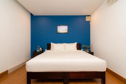 a bedroom with a blue wall and a white bed at The Cuckoo's Nest Hostel and Bar managed by Hoianese in Hoi An