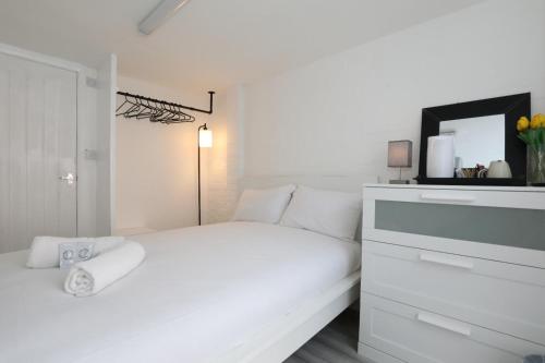 biała sypialnia z białym łóżkiem i komodą w obiekcie Anchor Guest House w Londynie