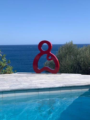 a large red sculpture sitting next to a swimming pool at Villa Nafsika stunning view on the Aegean Sea in Áyioi Apóstoloi
