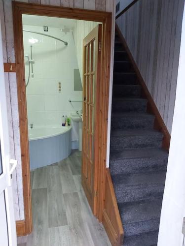 a bathroom with a staircase and a bath tub and a bathroom with a stairway at Poppy's Place Annex in Camelford North Cornwall in Camelford
