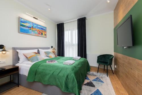 een slaapkamer met een bed met een groene deken bij Grano Green Comfort Residence by Renters Prestige in Gdańsk