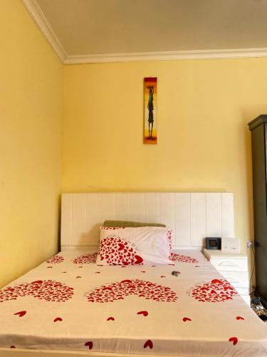 Cozy studio apartment في أروشا: غرفة نوم مع سرير مع زهور حمراء عليه