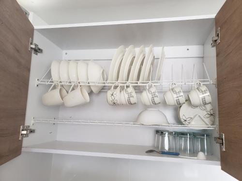 a cupboard filled with white coffee mugs at Apartamento amoblado con excelente ubicación en Pasto in Pasto