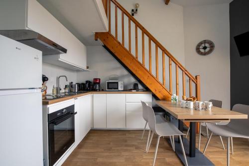 une cuisine avec une table en bois et un escalier dans l'établissement Appart pour 4 - Piscine - Au coeur de La Chaume, à Les Sables-dʼOlonne
