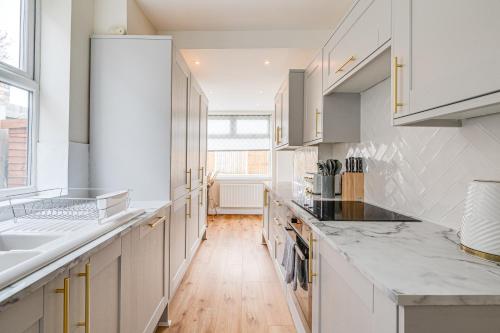 a kitchen with white cabinets and a wooden floor at Elegant 3 Bed House near Liverpool City Centre in Liverpool