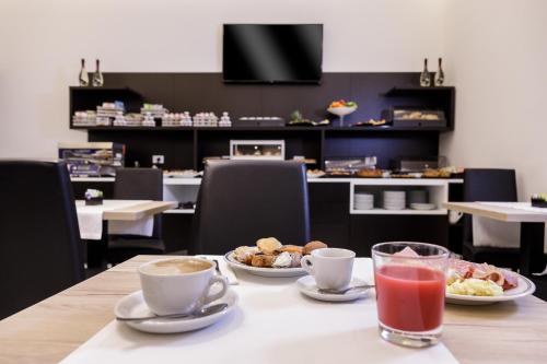 a table with plates of food and drinks on it at Best Western Hotel dei Mille in Naples