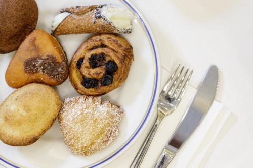 a plate of pastries on a table with a fork and knife at Best Western Hotel dei Mille in Naples