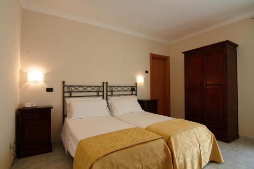 サン・ジョヴァンニ・ロトンドにあるHotel Villa San Pietroのベッドルーム1室(大型ベッド1台、木製キャビネット付)