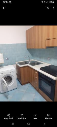 uma cozinha com um lavatório e uma máquina de lavar roupa em Monolocale em Palinuro