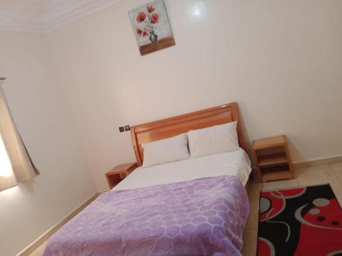 een slaapkamer met een bed met een paars dekbed bij Résidence hôtelière Nour in Dakhla