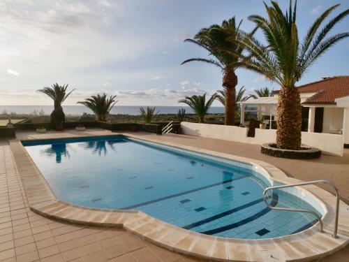 una piscina con palmeras y una casa en Finca Afortunada, en Las Puntas