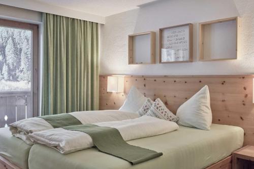 a bedroom with a large bed with white sheets and pillows at Bio Hotel Stillebach in Sankt Leonhard im Pitztal