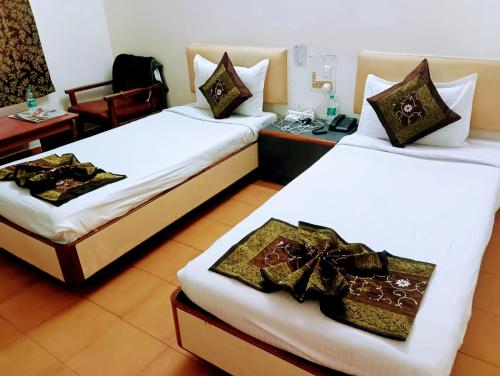 2 camas en una habitación de hotel con sábanas blancas en Hotel Ranjit Residency, en Hyderabad
