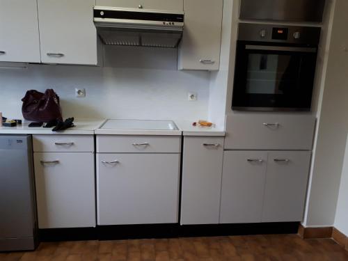 une cuisine avec des armoires blanches et un micro-ondes dans l'établissement Appartement dans résidence Le Saint Pierre, à Avignon