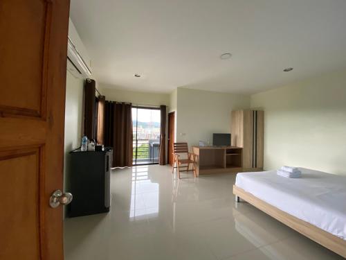 a bedroom with a bed and a table and a desk at Tha-ruea Residence in Thalang