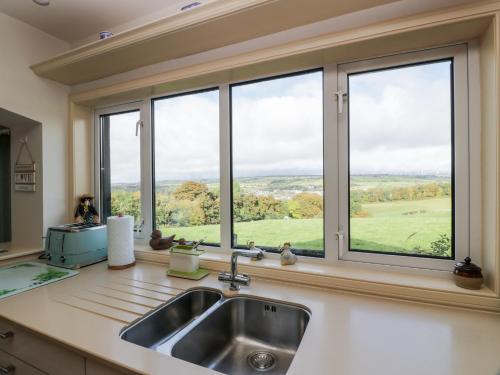 een keuken met een wastafel en een raam met uitzicht bij Whiteside Cottage in Darvel