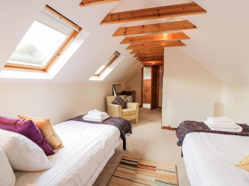 2 Betten in einem Schlafzimmer im Dachgeschoss mit Dachfenster in der Unterkunft Whiteside Cottage in Darvel