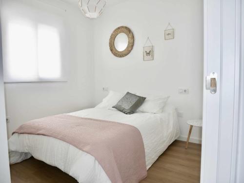a white bedroom with a bed and a mirror at Casa Carivid en el centro y con parking gratis in Sanlúcar de Barrameda