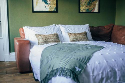 a bed with white sheets and pillows on a couch at The Main Street Burrow - Your Perfect Hideaway in Saint Boswells