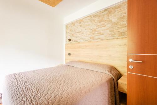 a bedroom with a bed and a brick wall at CROSINA HOLIDAY - Casa Lucia in Ledro