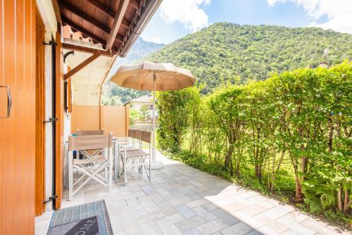 a patio with an umbrella and a table and chairs at CROSINA HOLIDAY - Casa Lucia in Ledro