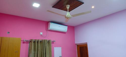 a room with a pink wall and a ceiling fan at Govind Niwas Homestay in Jagdalpur