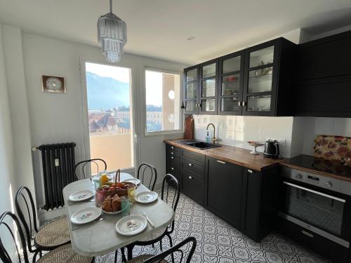 une cuisine avec une table et des chaises et une cuisine avec une fenêtre dans l'établissement Cocon vintage - T4 central et lumineux, à Annecy