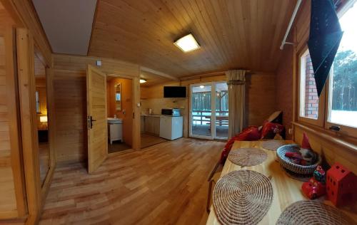 a large room with a wooden floor and a kitchen at Domki w Sosnowym Lesie in Rembów