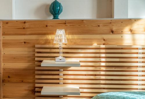 a bedroom with a wooden wall with a lamp at Casa Vacanze La Fenice - Casa Atlantica in Cava dʼAliga