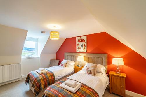 two beds in a room with an orange wall at Stags View with Hot Tub in Blairgowrie