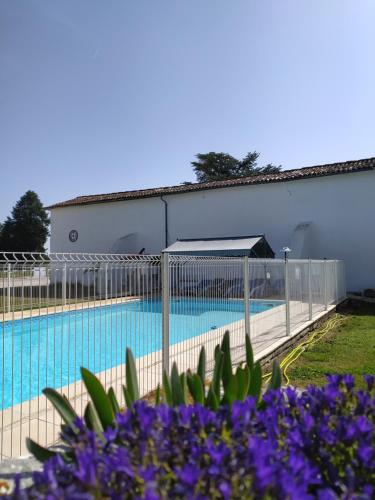a fence around a swimming pool with purple flowers at Domaine Moulin d'Elemiah in Gémozac