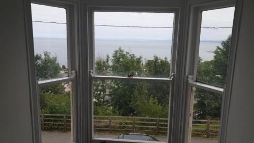 a window with a view of the ocean seen through it at Woodlands Bellevue Bed & Breakfast in New Quay
