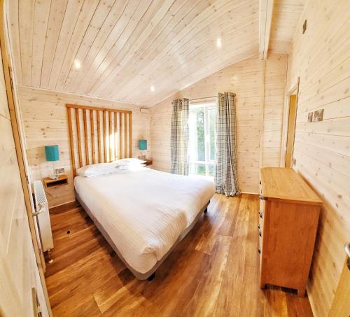 Skyline Lodge Loch Lomond Castle Lodges في بالوتش: غرفة نوم بسرير كبير وسقف خشبي