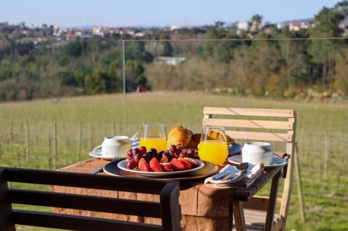a table with a plate of fruit and two glasses of orange juice at Quinta das Areias - Solar da Pena in Braga
